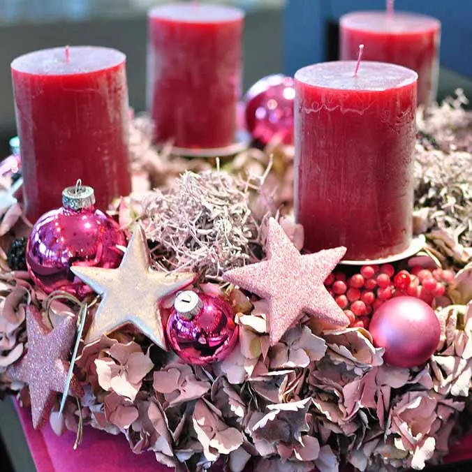 Adventsgesteck mit roten Kerzen und Sternen