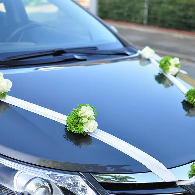 Autoschmuck aus weißen Bändern und Blüten