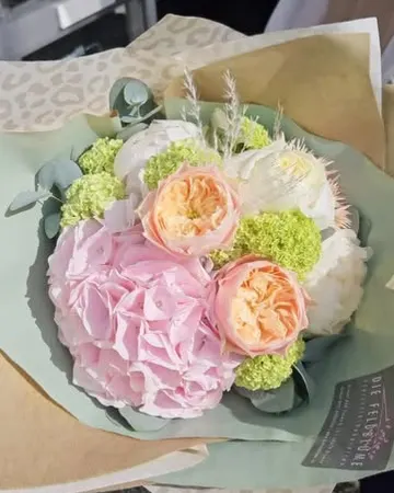 Strauß aus rosa Hortensie, Rosen und Schneeball, eingeschlagen in Papier der Feldblume