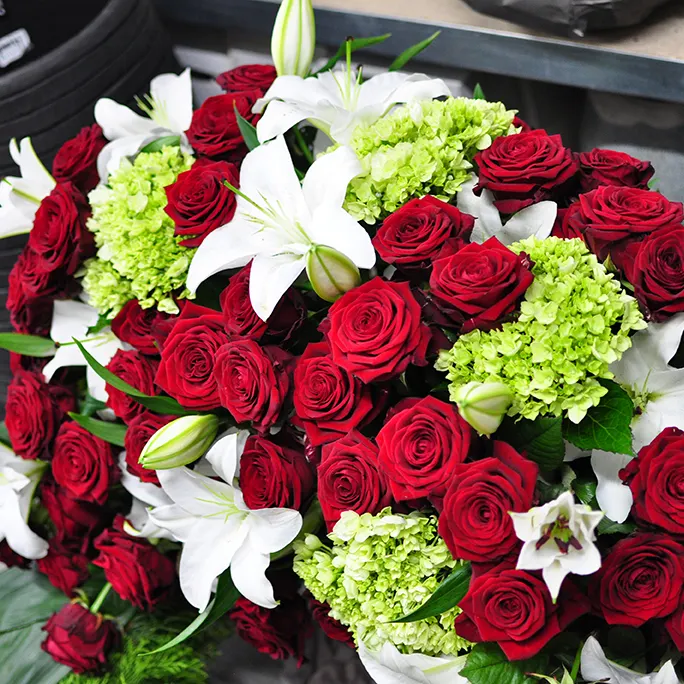 Trauergesteck mit weißen Lilien und roten Rosen